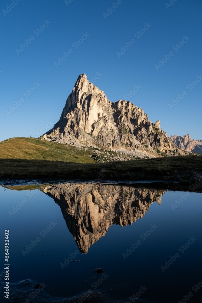 Scenic view of a rocky mountain reflecting on a lake on a sunny day