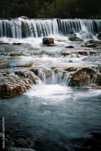 Vertical of a waterfall cascading down the rocks © Wirestock