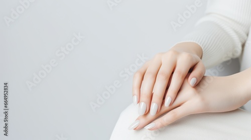 Beautifully groomed woman's hands with white nails against a light gray background.