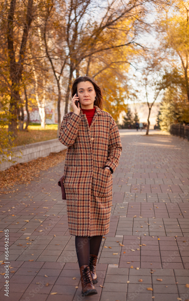 a girl walks in the park and talks on the phone. business concept