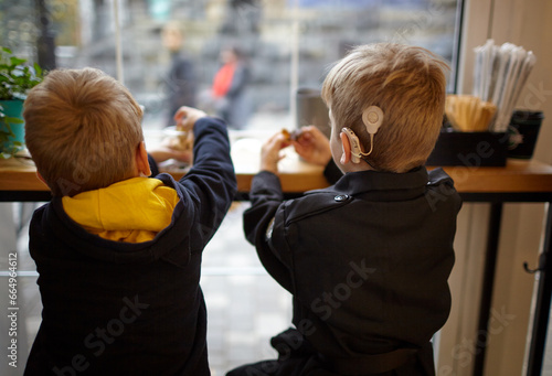 Boy have a Hearing Aids. Two twin brothers in a cafe. Selective focus, shallow depth of field photo