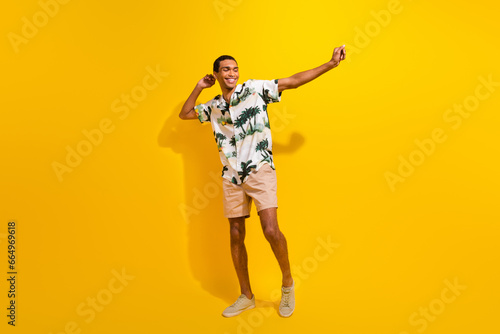 Full size photo of handsome young guy dancing have fun discotheque wear trendy palms print outfit isolated on yellow color background
