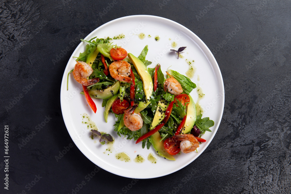 Salad with arugula, tomato, avocado and shrimp on a dark background. Salad with arugula, tomato, avocado and shrimp on a dark background.