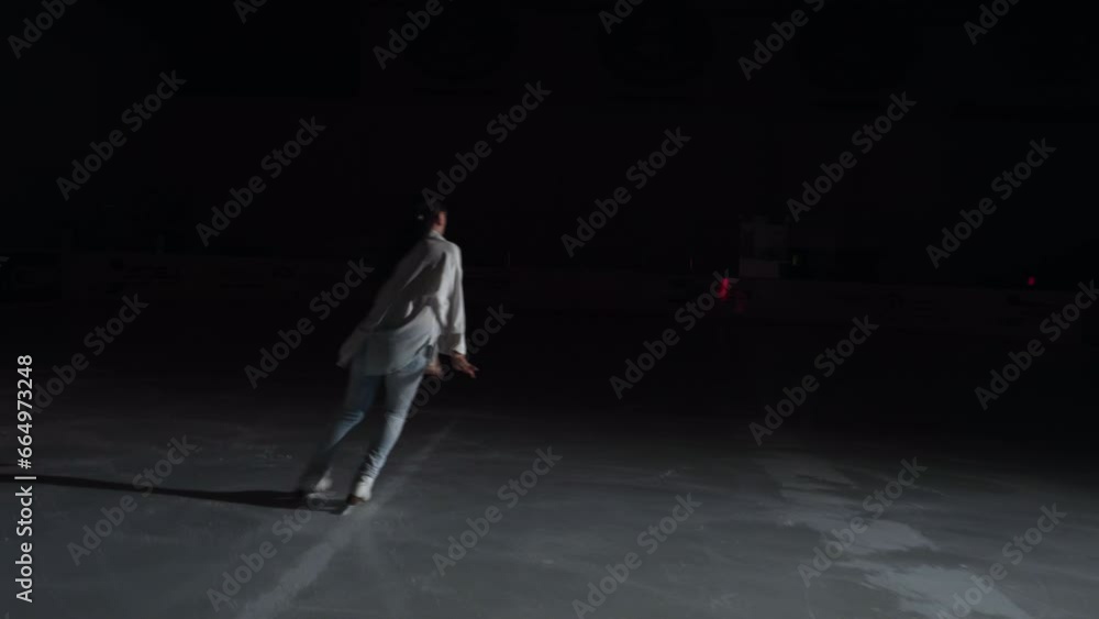 Camera follows a professional figure skater dance on the ice, goes into dark Camera follows a professional figure skater dance on the ice, goes into dark