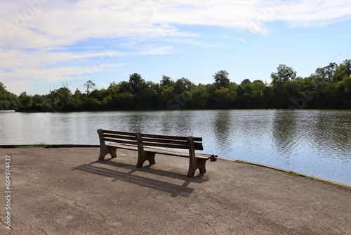 The empty park bench at the lake in the park.