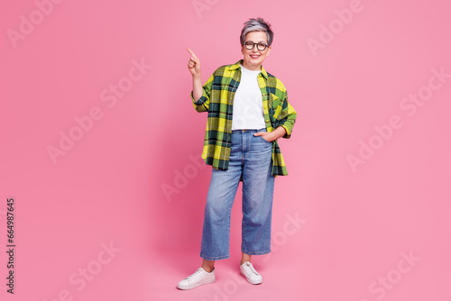 Full size photo of senior person with white gray hair dressed plaid shirt inidcating at logo empty space isolated on pink color background