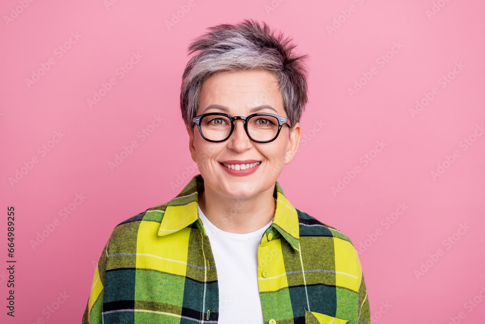 Photo of satisfied pleasant retired woman with short hairstyle wear checkered shirt smiling at camera isolated on pink color background