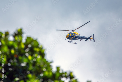A helicopter crosses the blue sky with clouds. Transportation. Urban.
