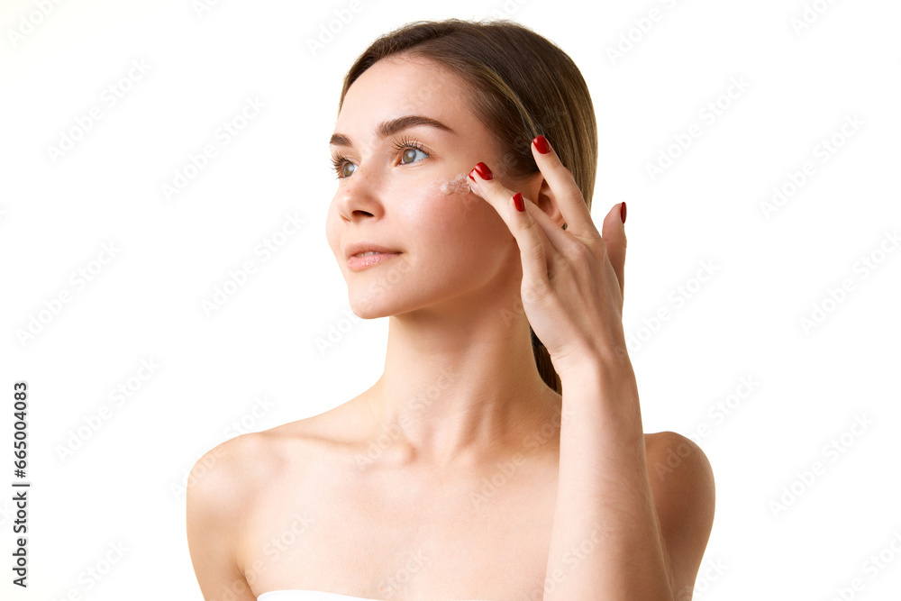 Pretty young girl with spotless, smooth, clear skin using face scrub for deep cleansing isolated over white studio background. Concept of natural beauty, skincare, cosmetics and cosmetology Pretty young girl with spotless, smooth, clear skin using face scrub for deep cleansing isolated over white studio background. Concept of natural beauty, skincare, cosmetics and cosmetology