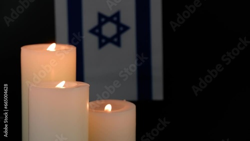 Israel flag and three different white burning candles on black background. Memorial and pray concept. Copy space for text.