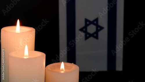 Israel flag and three burning candles on black background. Memorial and pray concept. Copy space for text. photo