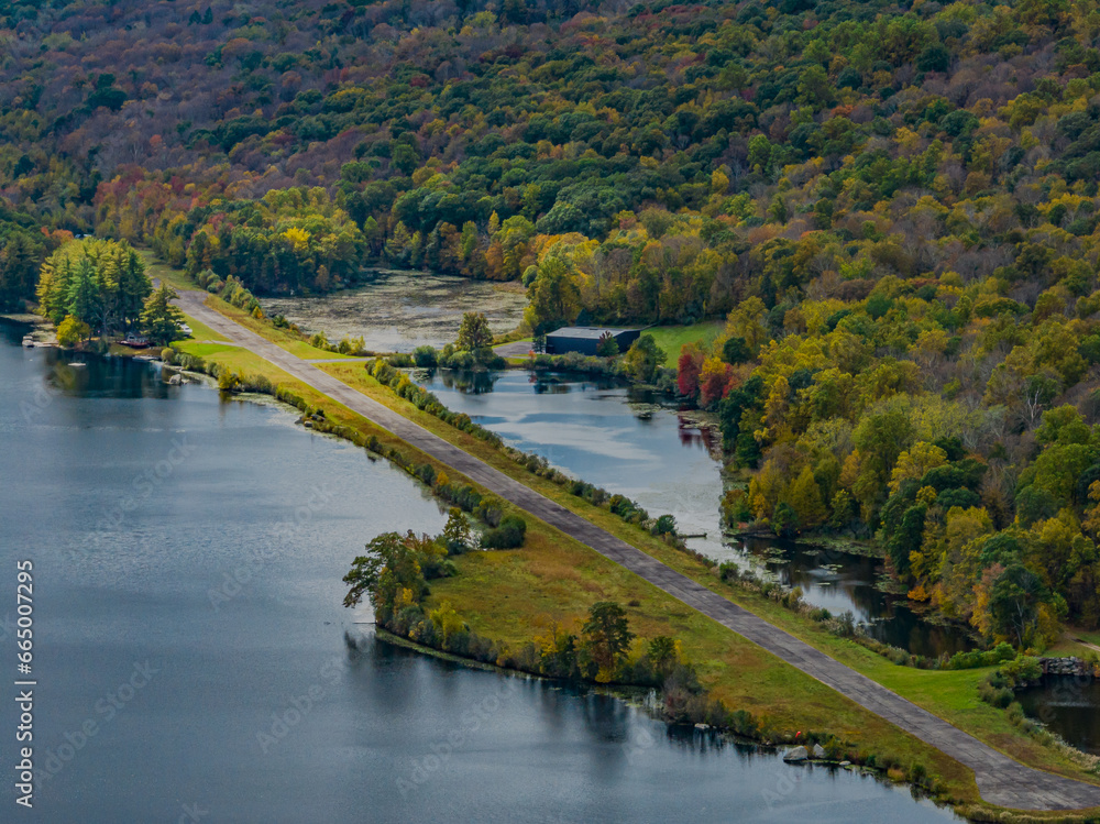 Obraz premium Aerial view of the countryside in Stormville, NY on a cloudy day during the colorful autumn season with a lake in view.