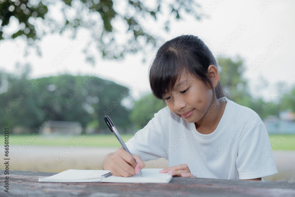 Little asian girl use pen writing on notebook Little asian girl use pen writing on notebook