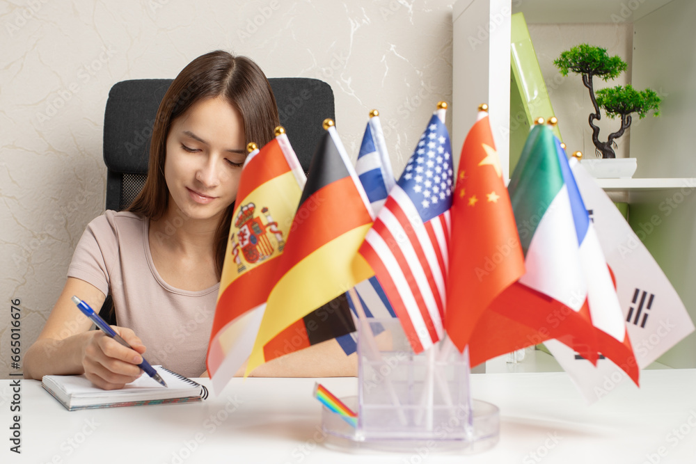 learning languages, immigration, working abroad, paperwork, student at a desk with flags of different countries - obrazy, fototapety, plakaty 