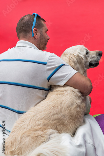 40 year old man hugging his golden retriever dog as they sit together