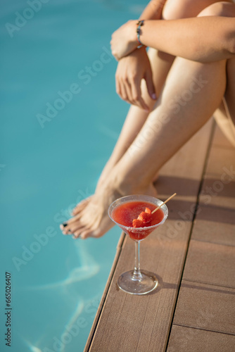 Girl having a strawberry mojito next to the swimming pool