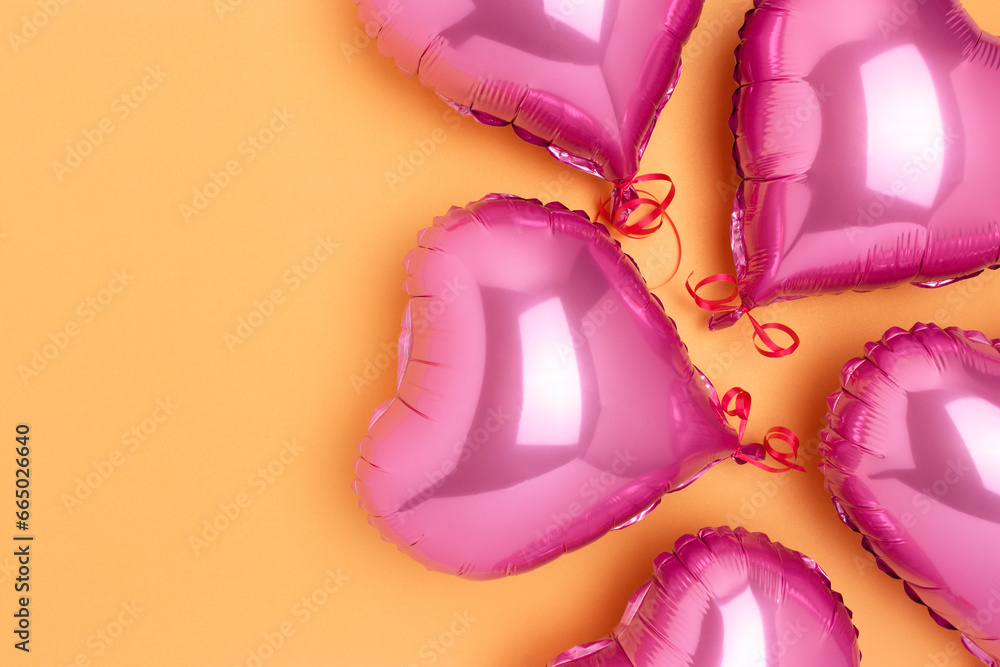 Pink inflatable foil balloons in a heart shape. Concept on a gold colored background with place for text. Pink inflatable foil balloons in a heart shape. Concept on a gold colored background with place for text.