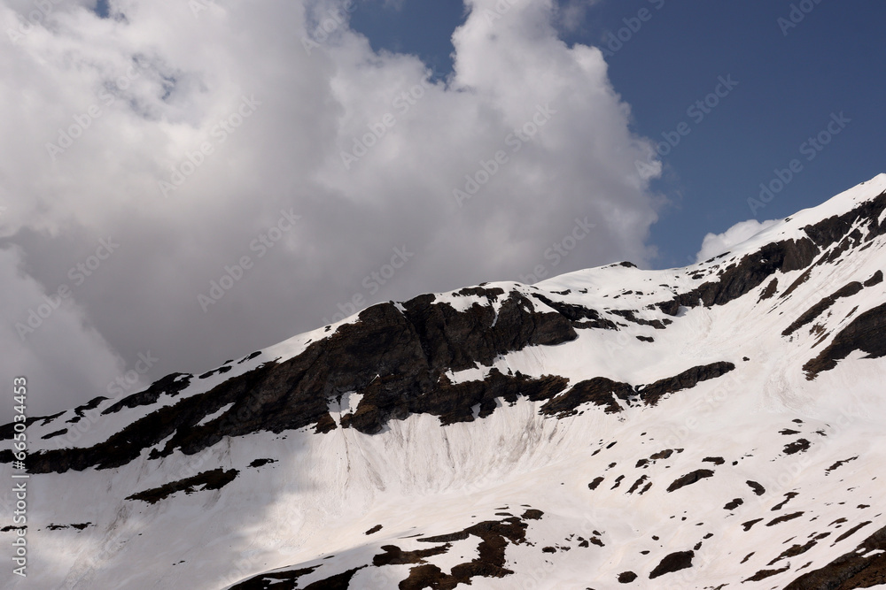 Snow Covered Mountain Peak With Clouds and Blue Sky