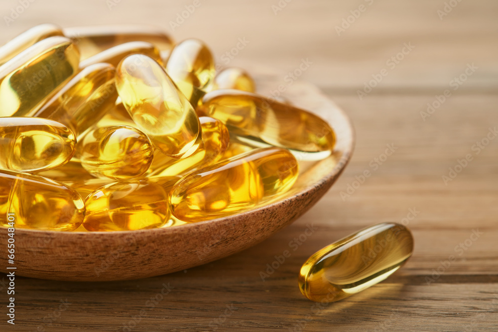 Close up capsules with Vitamin D, E or Omega 3,6,9 fatty acids in bottle on old wooden backgrounds. Food supplement oil filled fish oil. Natural supplements for healthy good life concept. Banner. Close up capsules with Vitamin D, E or Omega 3,6,9 fatty acids in bottle on old wooden backgrounds. Food supplement oil filled fish oil. Natural supplements for healthy good life concept. Banner.