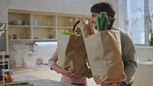 Couple sorting purchased products standing at cozy kitchen countertop close up. 