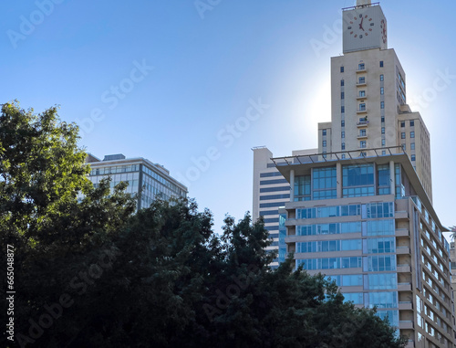 A large glass skyscraper rising in front of beautiful sunshine in downtown Dallas Texas. The Dallas skyline includes this large and pointed skyscraper.