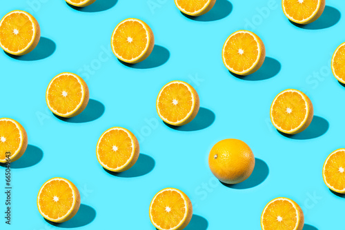 Fototapeta Naklejka Na Ścianę i Meble -  Trendy Summer food pattern made with orange slice with one whole orange on bright light blue background. Minimal summer concept.