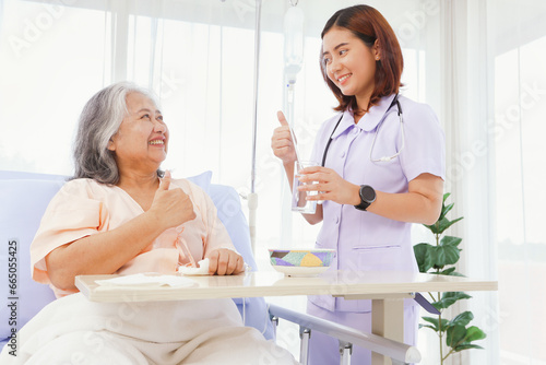 Female nurse takes care of elderly healthcare patients friendly manner Help willingly show thumbs up after eating to encourage patients feel good and encourage patients to recuperate in the hospital.