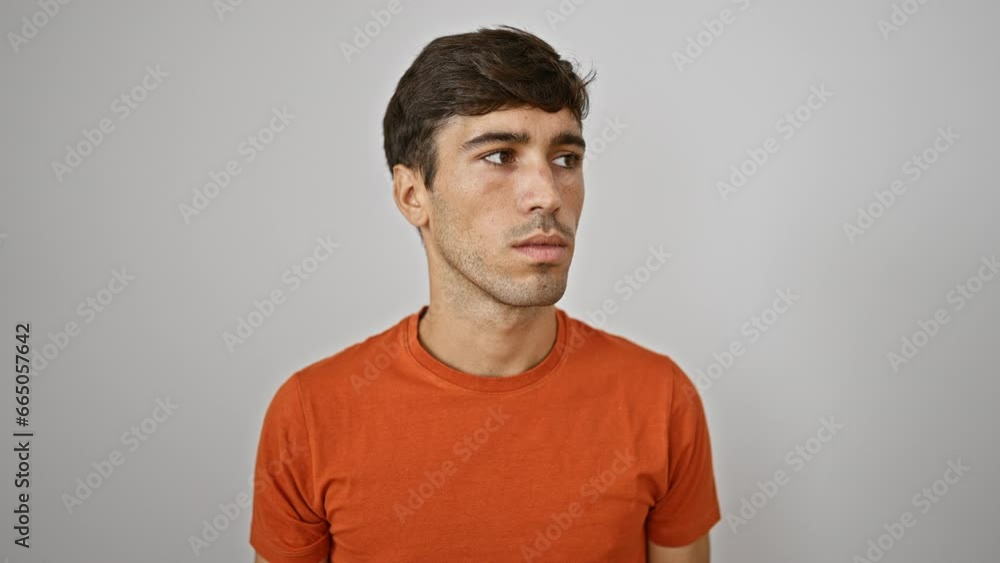 Young, handsome hispanic man feeling the noise too loud, seriously covering ears with hands standing by an isolated white background, looking away in concentration Young, handsome hispanic man feeling the noise too loud, seriously covering ears with hands standing by an isolated white background, looking away in concentration