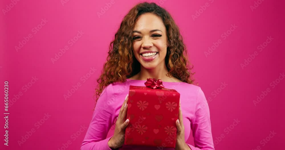 Excited young woman holds gift box and reveals face, pink ribbon, anniversary Excited young woman holds gift box and reveals face, pink ribbon, anniversary