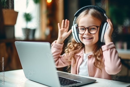 a smiling little girl in headphones having a video call distant class with a teacher using a laptop
