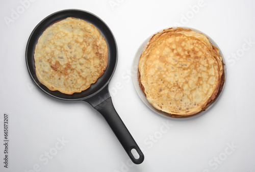 Frying pan with pancakes on white background. Top view