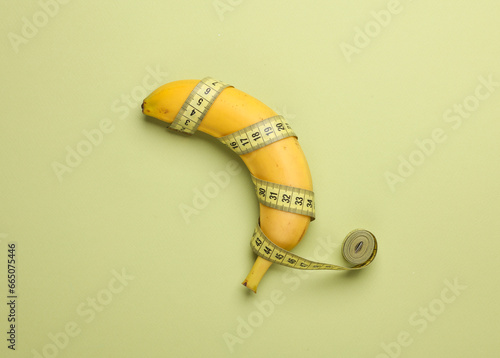 Banana wrapped with measuring tape on a green background