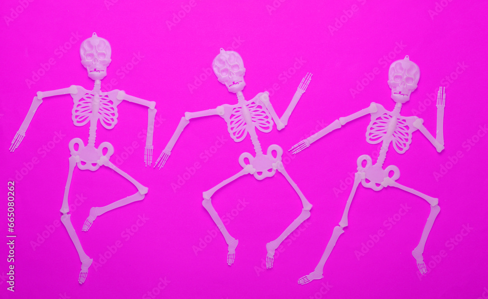 Halloween background. Dancing skeletons on purple background. Top view Halloween background. Dancing skeletons on purple background. Top view