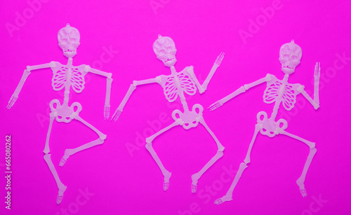 Halloween background. Dancing skeletons on purple background. Top view