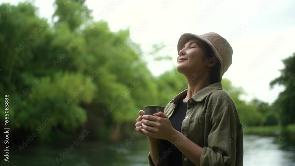 Happy woman breathing fresh air and drinking coffee near river forest campsite in the morning. Relax and vacation time with nature. Human and natural concept. Happy woman breathing fresh air and drinking coffee near river forest campsite in the morning. Relax and vacation time with nature. Human and natural concept.