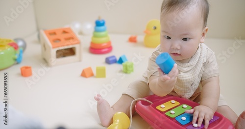 Portrait Of Adorable Happy little Asian baby child Toddler playing with colorful toy on floor living room, Educational game for baby and toddler