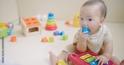 Portrait Of Adorable Happy little Asian baby child Toddler playing with colorful toy on floor living room, Educational game for baby and toddler