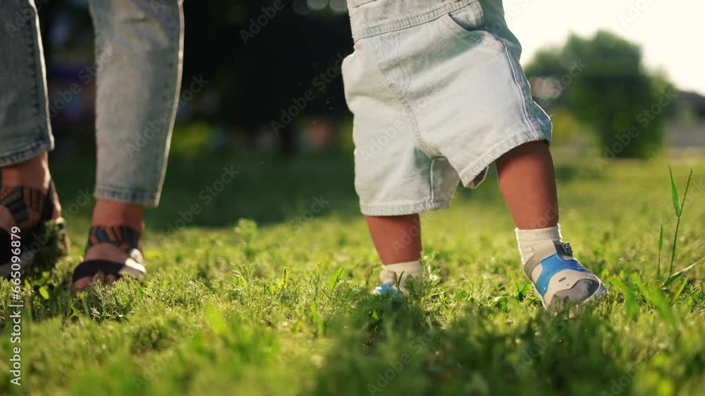 baby first steps. happy family a kid dream concept. baby walks on the grass learns to walk in the city park lifestyle close-up. baby first steps in nature. mom teaches son to walk baby first steps. happy family a kid dream concept. baby walks on the grass learns to walk in the city park lifestyle close-up. baby first steps in nature. mom teaches son to walk