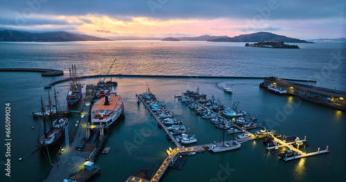 Sunset lighting over San Francisco Bay with Alcatraz and Hyde St Pier lit up at night aerial