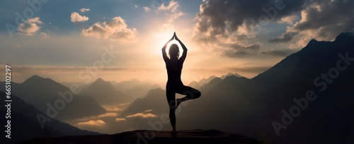 silhouette of a woman practicing yoga in the summit with mountain Background. © Anowar