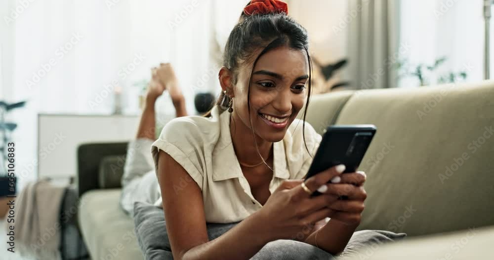 Woman, phone and lying on sofa for communication with smile for conversation, typing in living room of home. Indian, person and smartphone for texting with internet or technology on couch in lounge Woman, phone and lying on sofa for communication with smile for conversation, typing in living room of home. Indian, person and smartphone for texting with internet or technology on couch in lounge
