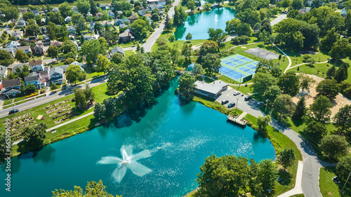 Aerial over Lakeside Pond with fountain near playground and tennis courts in neighborhood photo