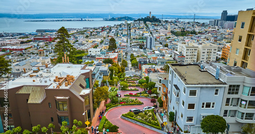 Winding Lombard Street with cars going downhill with distant Coit Tower aerial photo