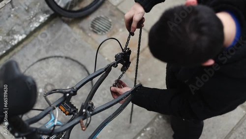 A young man is threading a bicycle chain. photo