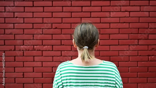 Dead end concept, rear view of casual brunette female facing the red brick wall