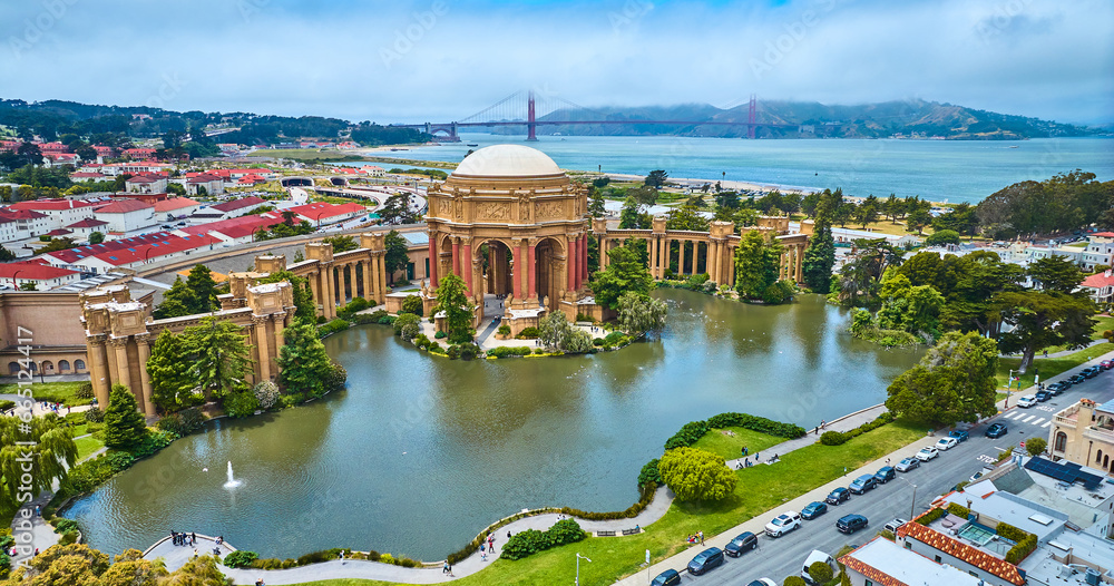 Pond around open rotunda and colonnade of Palace of Fine Arts with Golden Gate Bridge aerial