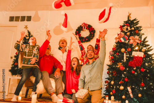 Multi-Generation Family Exchanging And Opening Gifts Around Christmas Tree At Home. Christmas family portrait - family sitting on floor front of beautiful Christmas tree.