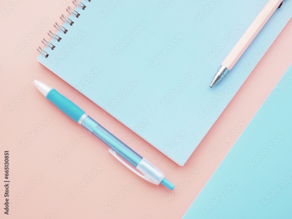 Pastel pink and blue background with notebook and pen Pastel pink and blue background with notebook and pen