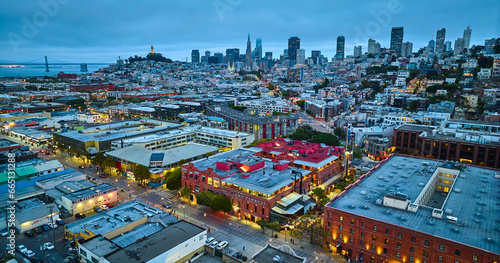 Fishermans Wharf aerial at dusk with lights on in the city and downtown skyscrapers in distance