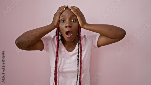 Wow! african american woman with beautiful braids expresses amazing surprise, standing over isolated pink background. incredible worried expression, mouth wide open, an adult female portrait.